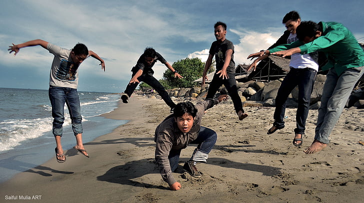 six person doing stunt on sea shore during daytime