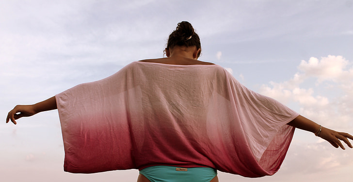 low angle photograph of woman wearing pink blouse and teal bikini bottom arm wide open