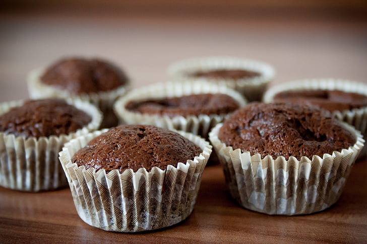 seven chocolate cupcakes on brown wooden surface