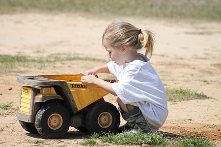 girl holding yellow and black Tonka drumptruck toy