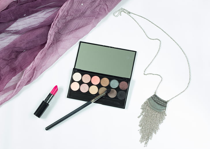 black eyeshadow palette with pink lipstick and brush