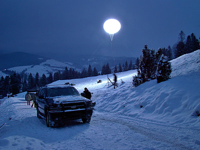 black vehicle parked beside snow mound at night time