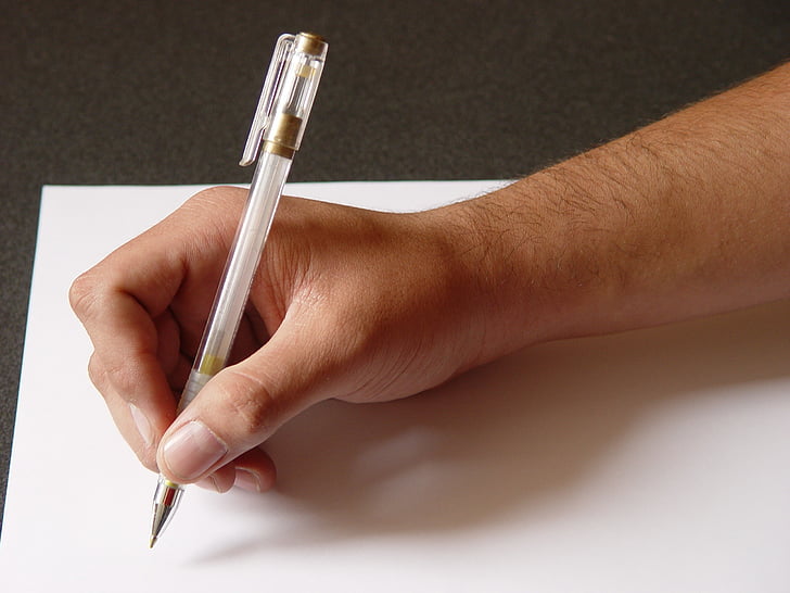 person holding pen writing on white printing paper