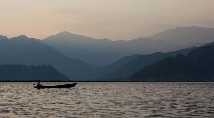 person riding boat sailing on body of water during dawn
