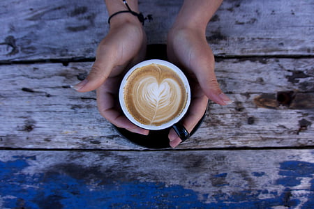 person holding latte on black ceramic cup