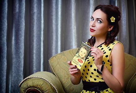 woman in yellow and black polka-dot sleeveless top sitting on sofa chair