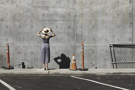 woman wearing gray dress and hat near wall