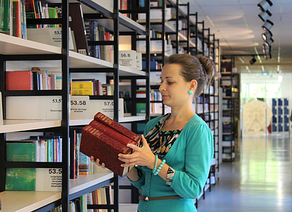 woman wearing teal top holding books