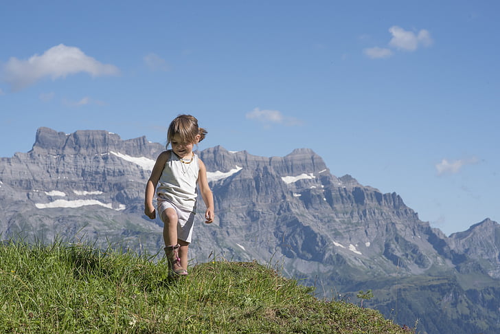 girl standing on grasses within mountain range
