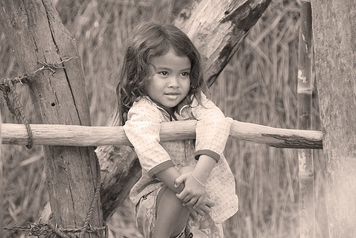 grayscale photo of girl beside log