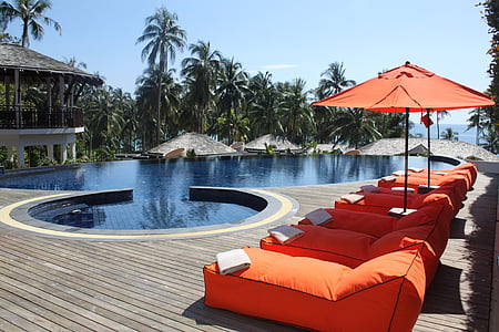 pile of orange patio lounge chairs near swimming pool