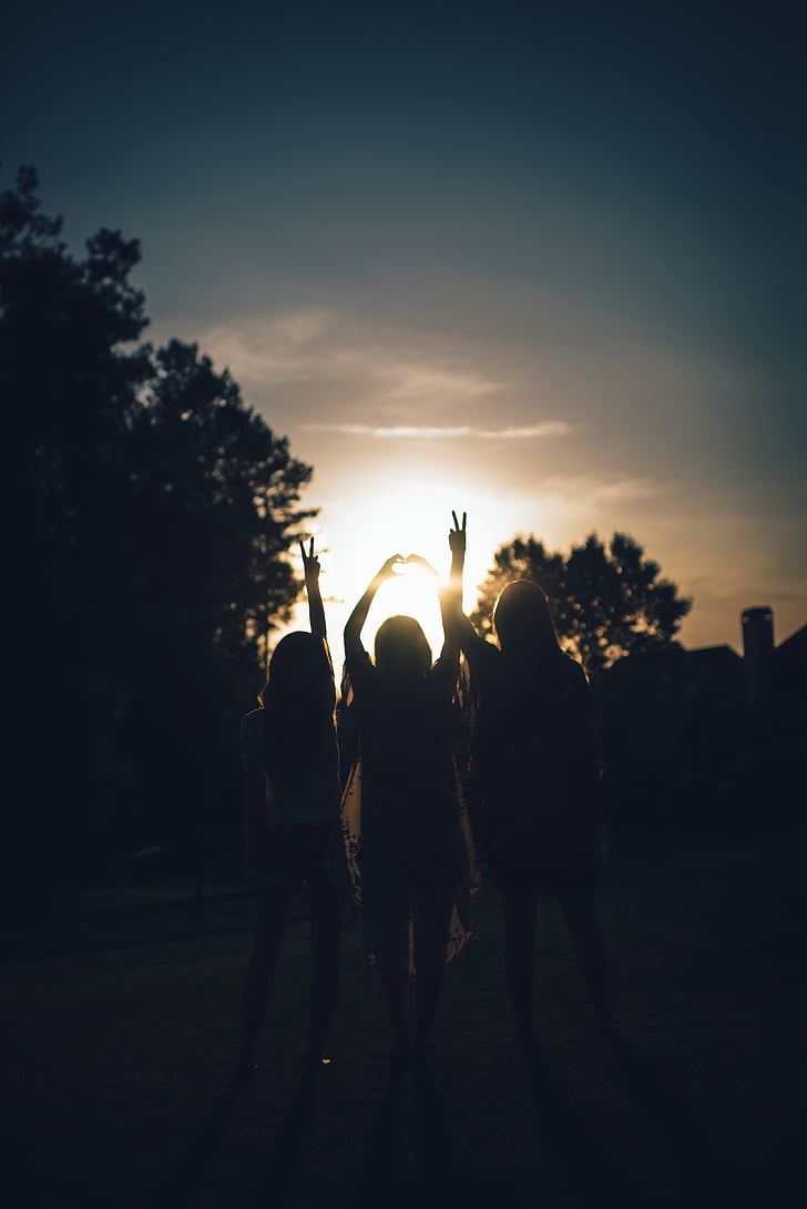 silhouette photo of three girls on open park