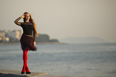 woman wearing black dress near the ocean