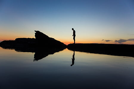 silhouette photo of person near body of water at daytime