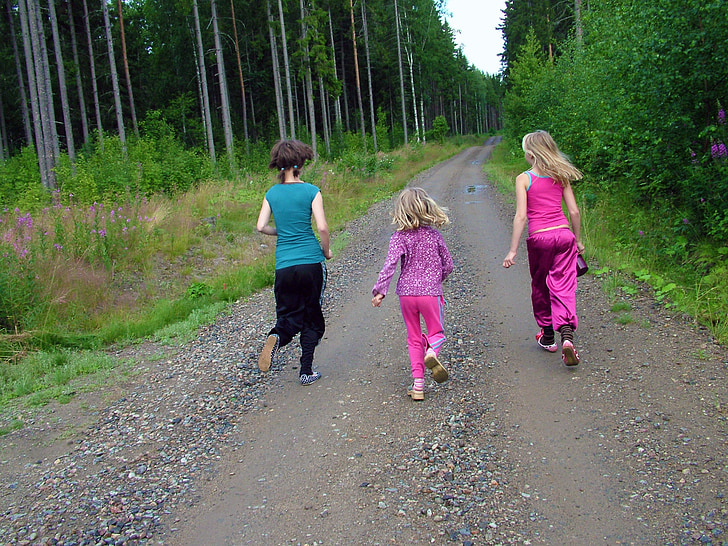 three girls walking on brown pathway