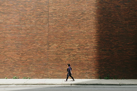 woman walking down the street along red brick wall