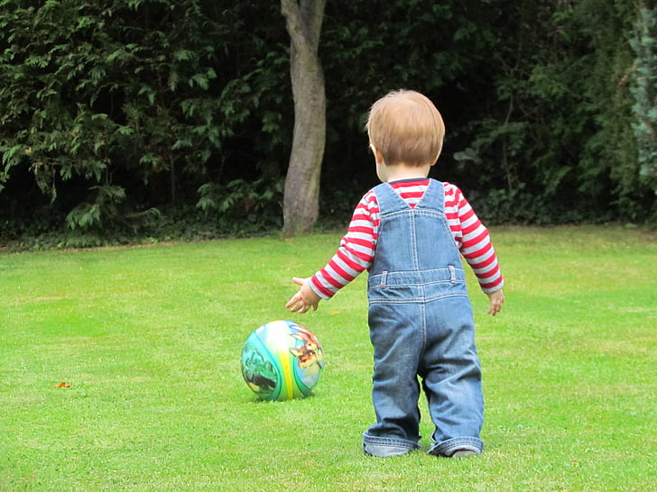 boy walking towards ball at daytime