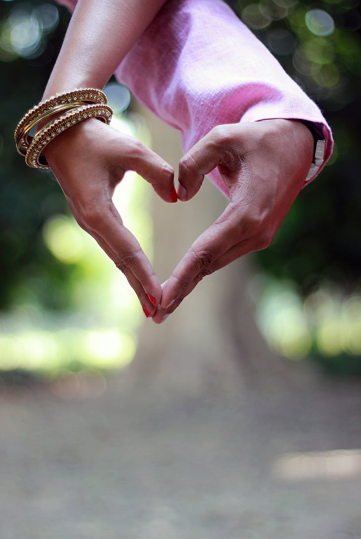 couple's hands forming heart gesture