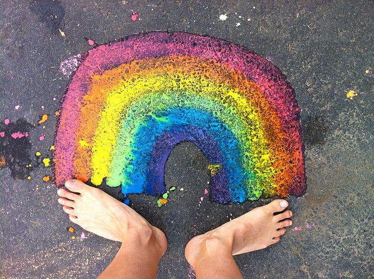 person standing in front of rainbow painting