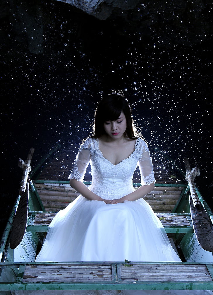 woman wearing white floral wedding dress sitting on bench