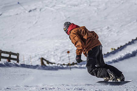 person wearing brown snowsuit and riding snowboard at daytime