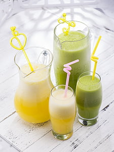 four yellow and green smoothies on glasses