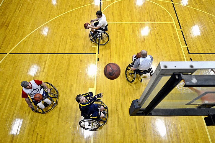 four person riding on wheelchairs playing basketball