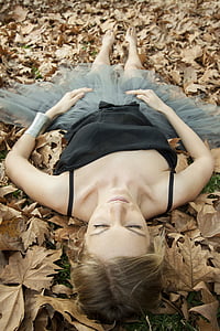 woman wearing black camisole and gray tutu skirt lying on brown leaves