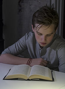 boy wearing gray henley shirt reading book