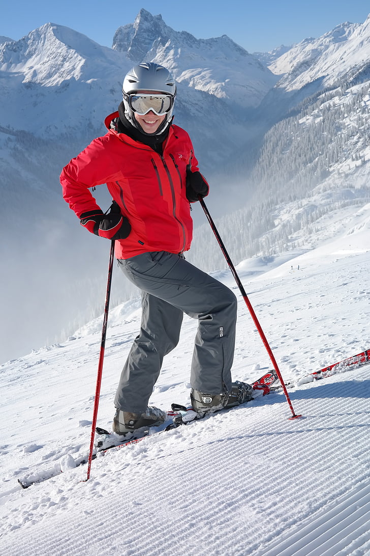 person in red jacket doing snow ski while holding ski poles during daytime