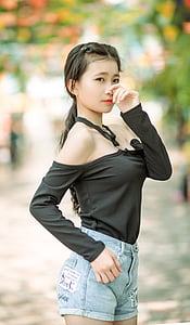 woman wearing black off-shoulder long-sleeved top and blue denim short shorts