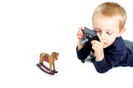 boy taking a picture of rocking horse toy