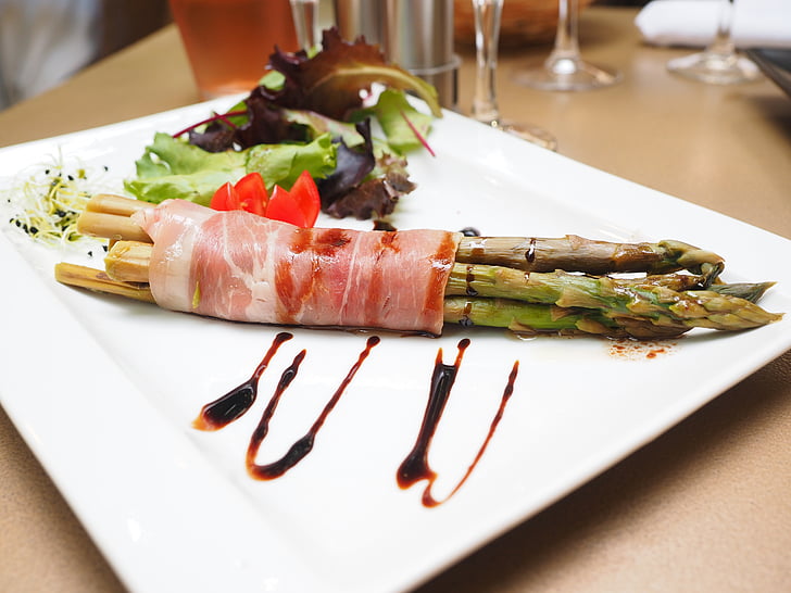 asparagus wrapped with bacon on white plate