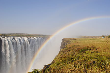 rainbow beside waterfall during daytime
