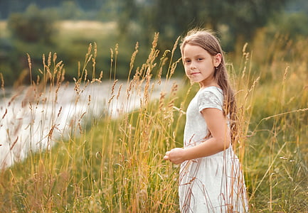 girl in white dress standing in wheat field
