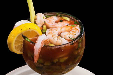 shrimp soup with spring onions filled clear drinking glass with sliced lemon on edge closeup photo