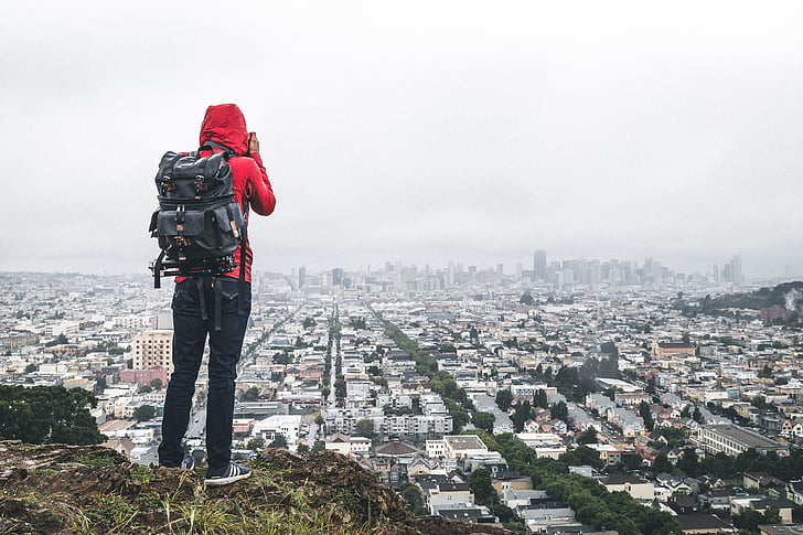 man standing on clip overlooking the city while taking photography