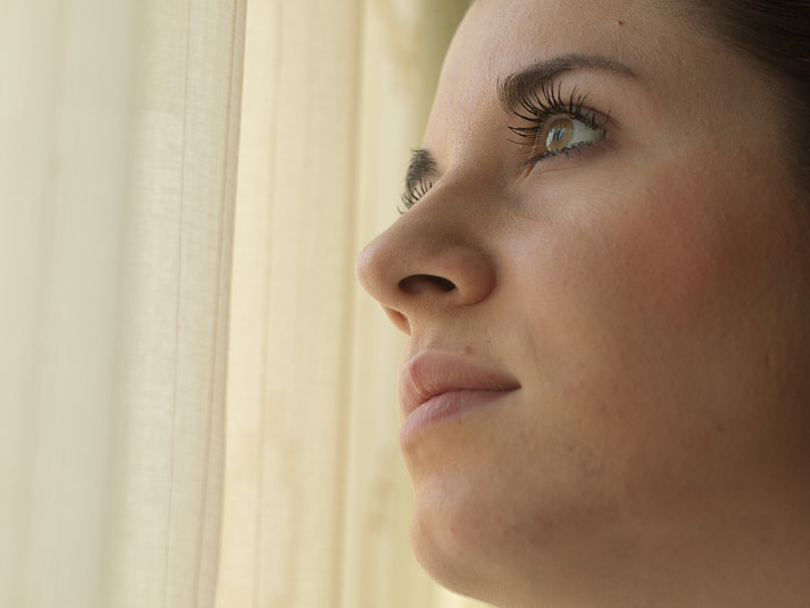 women's face near to window curtain