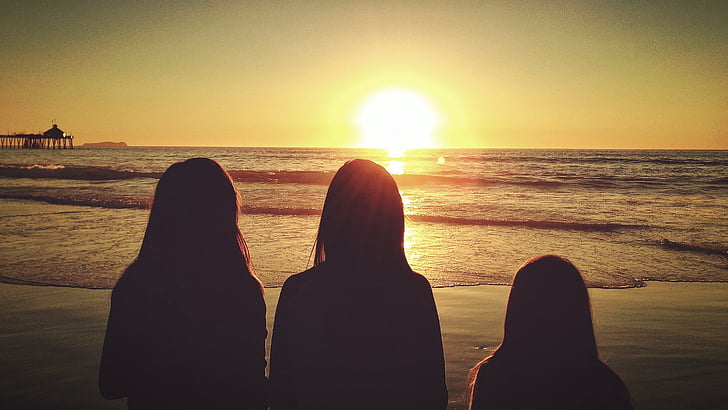 silhouette of three persons standing on seashore