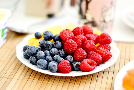 selective focus photography of plate of raspberries and blueberries