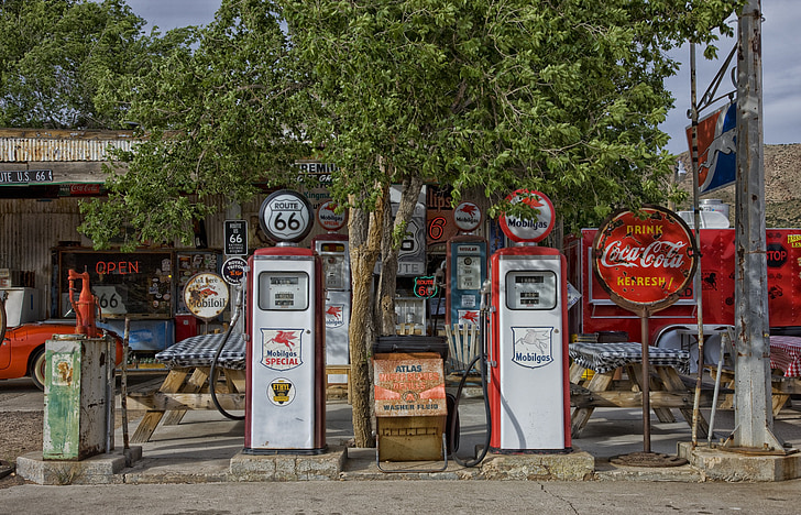two white-and-red gasoline fuel pump station near tree at daytime