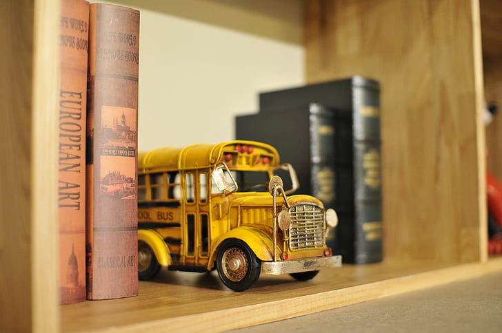 yellow school bus die-cast metal scale model on bookshelf