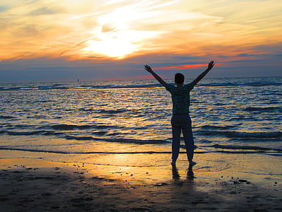 man standing on seashore during sunset