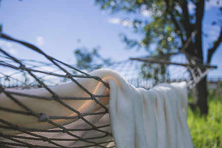 white blanket on gray rope hammock outdoor during daytime