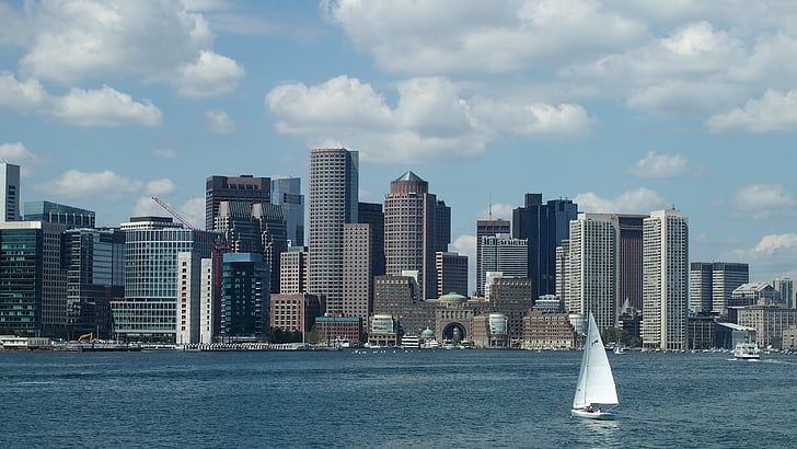 sail boat on body of water in distant of skyscrapers