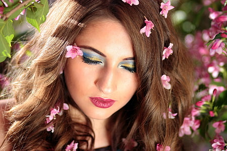 woman wearing blue mascara with pink flowers on her hair