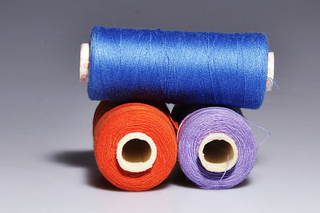 photo of blue, orange, and purple threads with spools