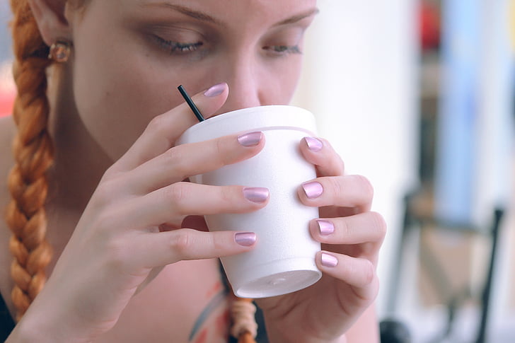 woman drinking on white disposable cup