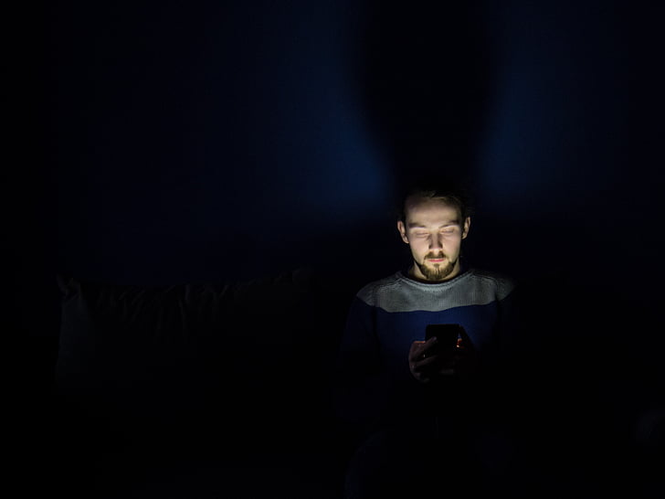 man in gray crew-neck shirt in dark room