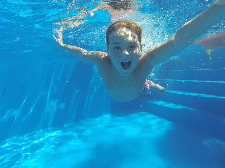 underwater photography of boy wearing red shorts